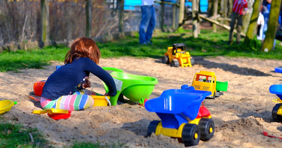 Kind buddelt und spielt im Sand