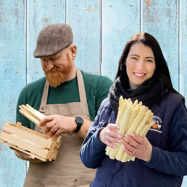 Zwei Saisonkräfte bieten frischen Spargel an.