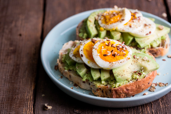 2 Scheiben Vollkornbrot mit Avocado und Ei auf einem Teller